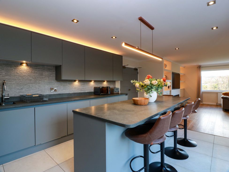 A kitchen with a bar island and stools at Cramar Cottage