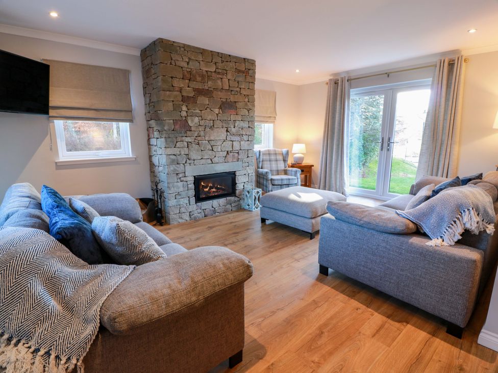 A living room with a fireplace and seating area at Cramar Cottage