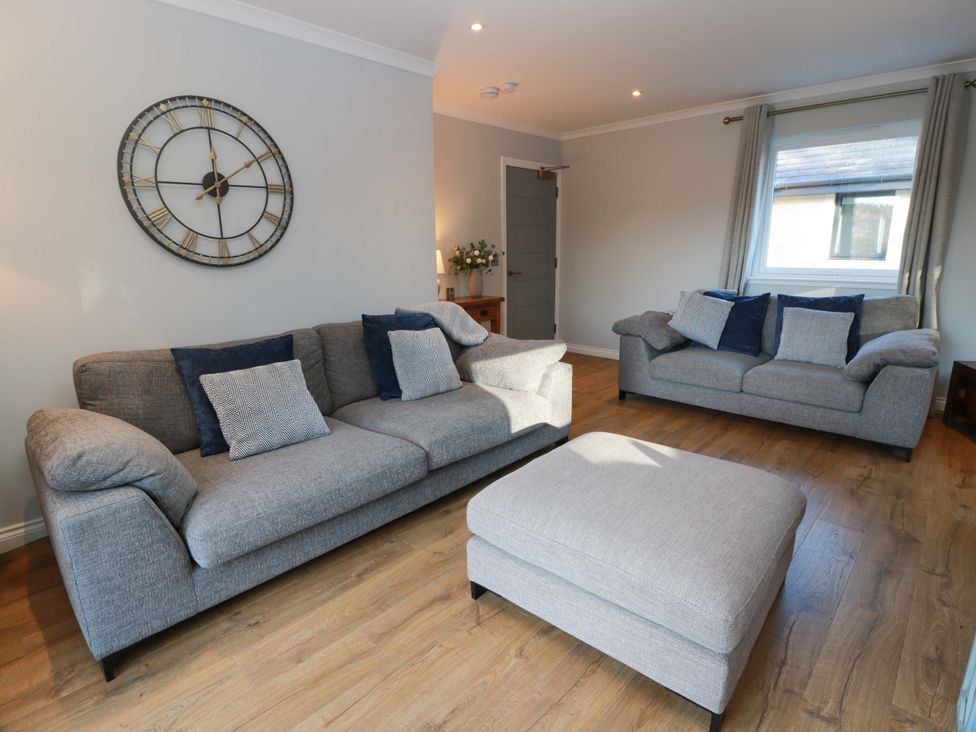 A living room with sofas and a wall clock at Cramar Cottage