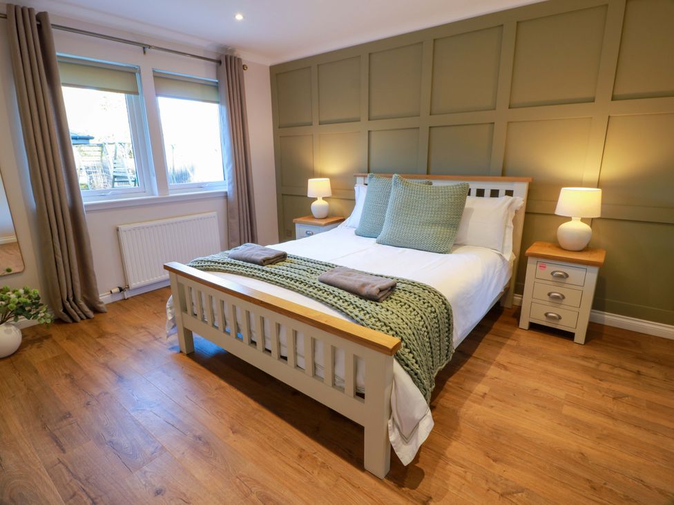 A bedroom with a bed and side tables at Cramar Cottage
