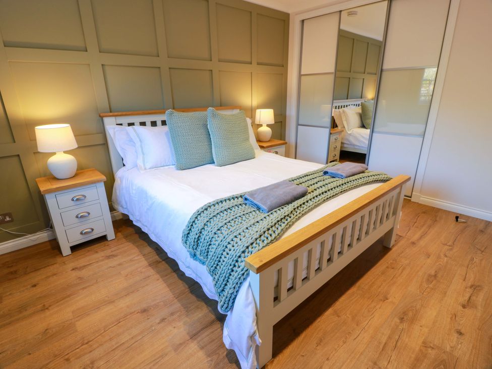 A bedroom with a bed and nightstand at Cramar Cottage