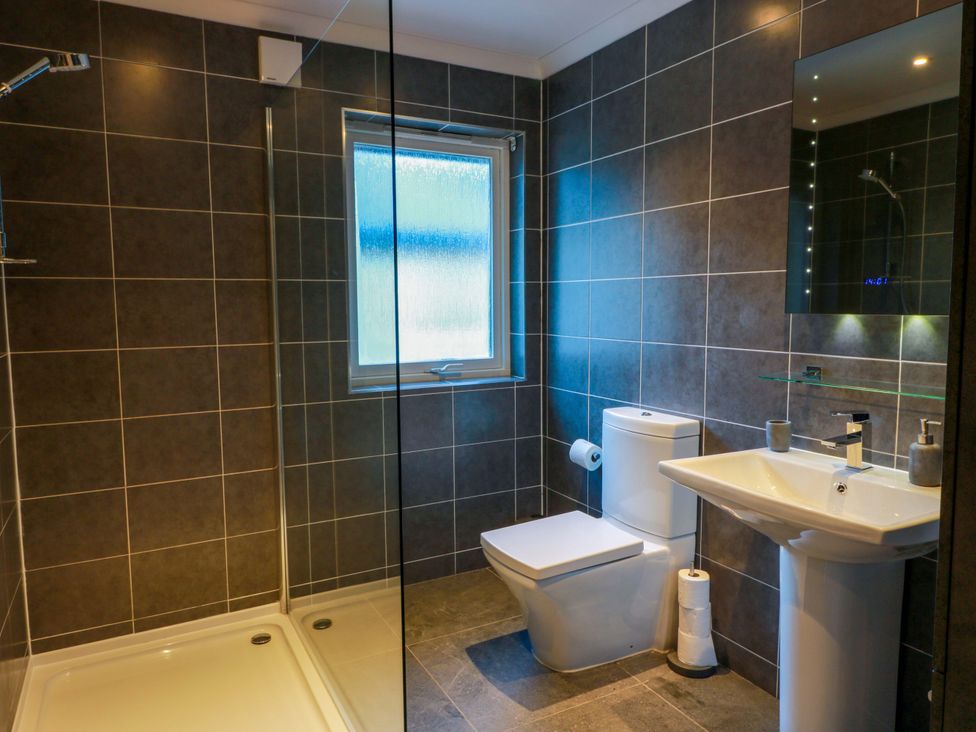 A bathroom with a shower, toilet, and sink at Cramar Cottage