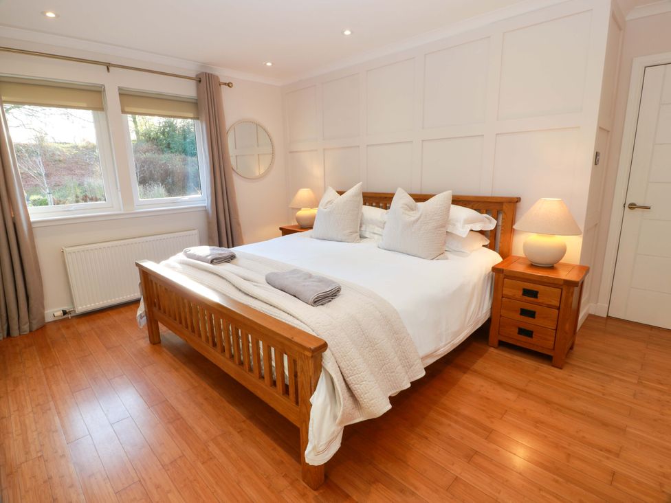 A bedroom with a bed and side table at Cramar Cottage