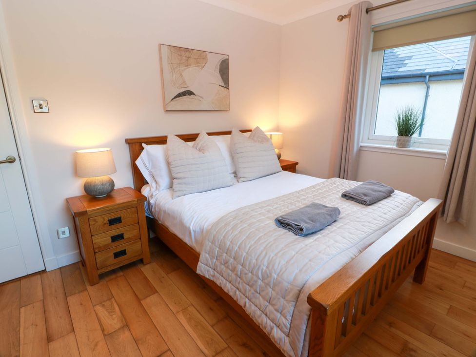 A bedroom with a wooden bed and bedside table at Cramar Cottage
