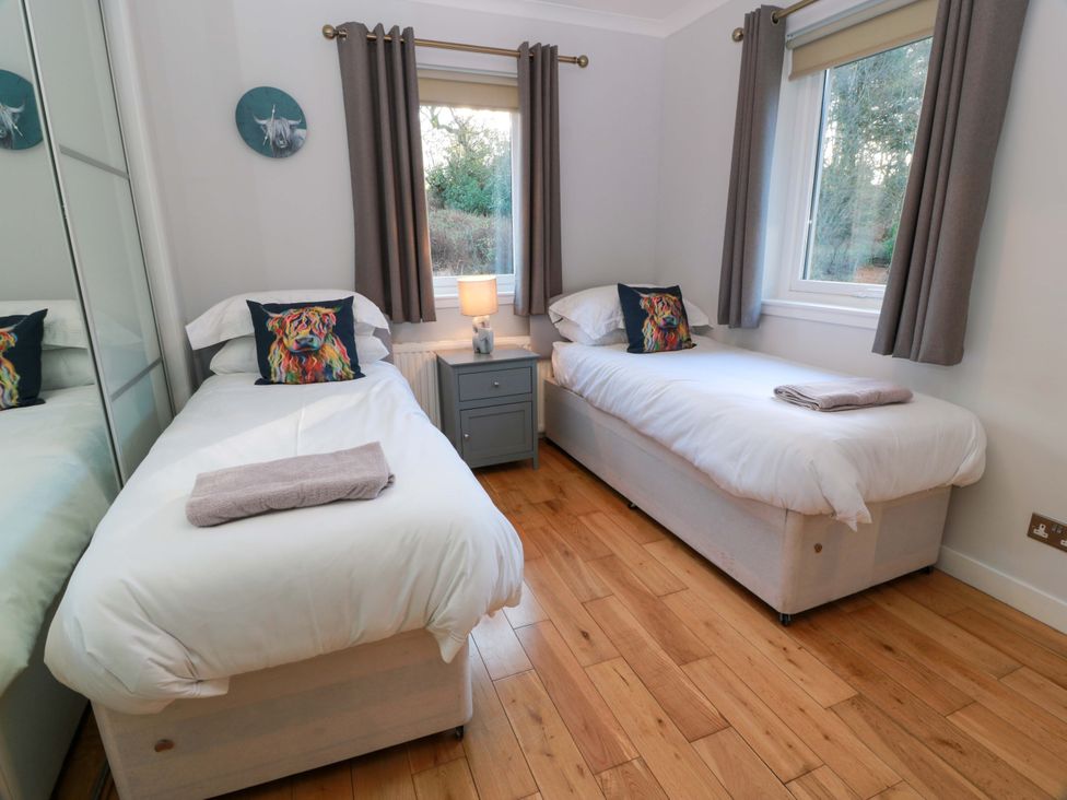 A bedroom with two beds and a nightstand at Cramar Cottage