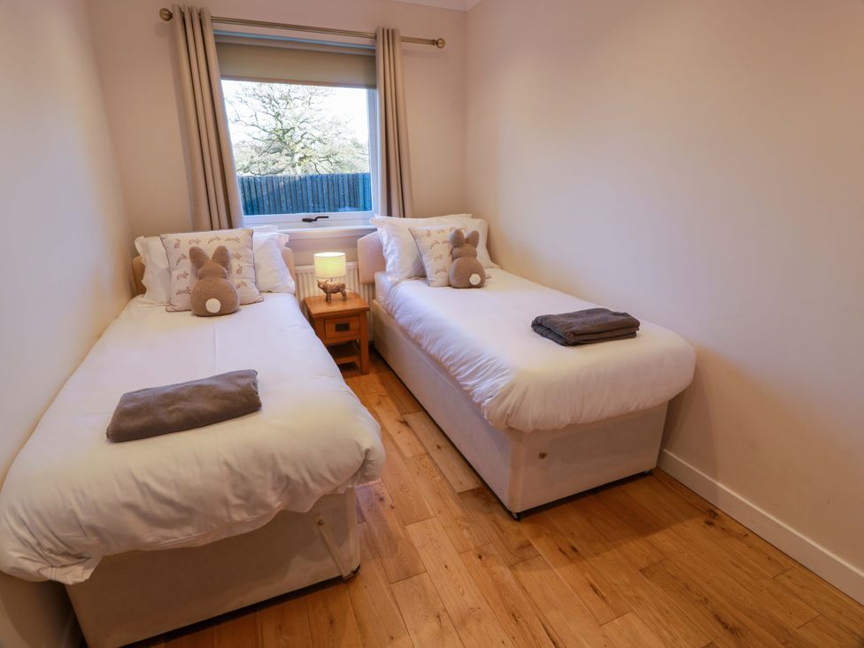 A bedroom with two single beds and a nightstand at Cramar Cottage