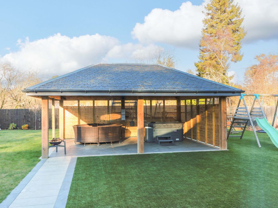 A gazebo with outdoor furniture and hot tub in a garden at Cramar Cottage