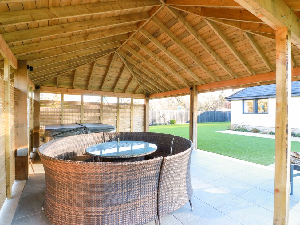 An outdoor seating area with a round table and chairs in a gazebo at Cramar Cottage
