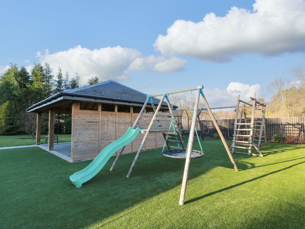 An outdoor play area with a slide and swings at Cramar Cottage