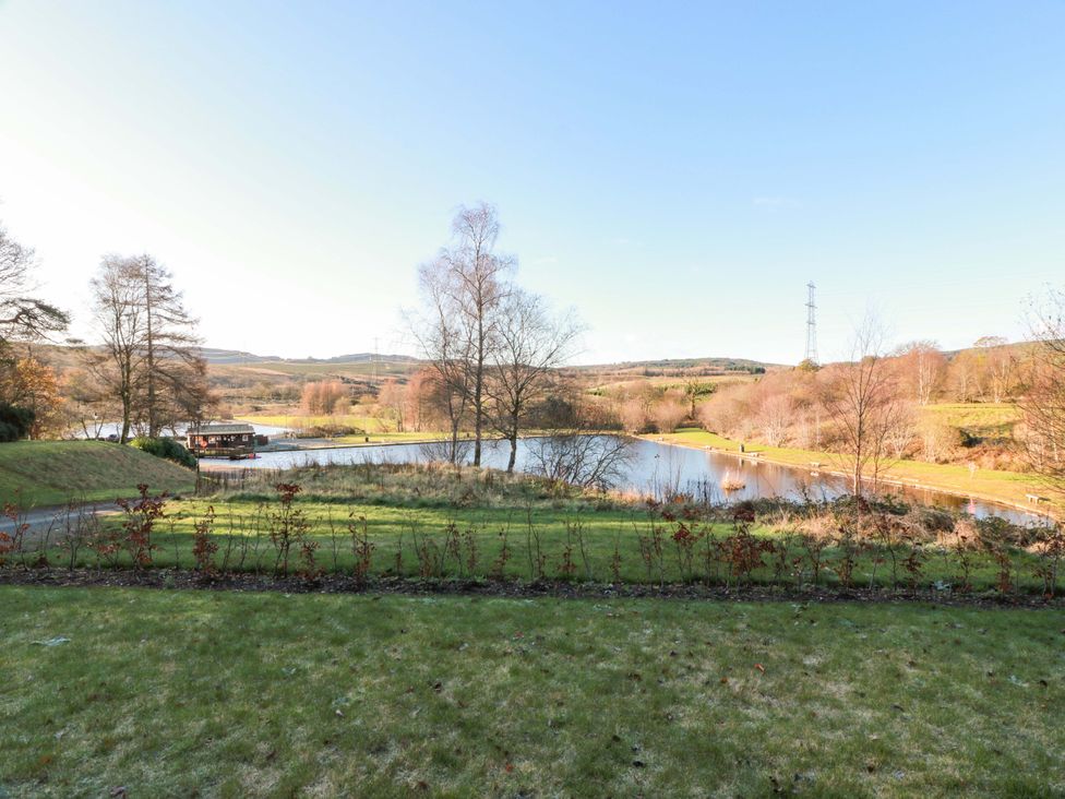A view of a lake with trees and grassland at Cramar Cottage