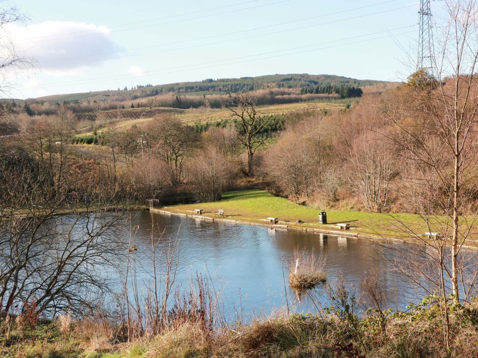 A lake with benches and trees near the water at Cramar Cottage 