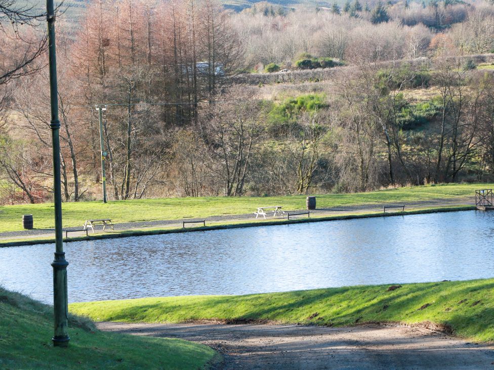 A lake with grass and park benches at Cramar Cottage in 