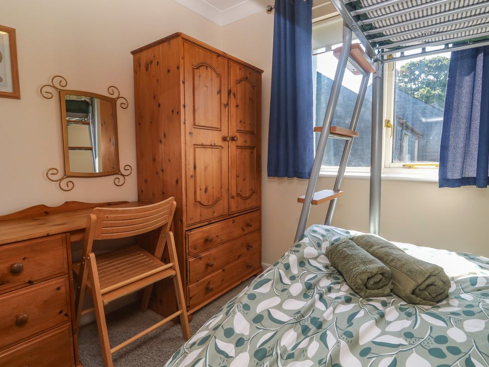 A bedroom with a bed, wardrobe, desk, and a ladder at Stargazy, Falmouth
