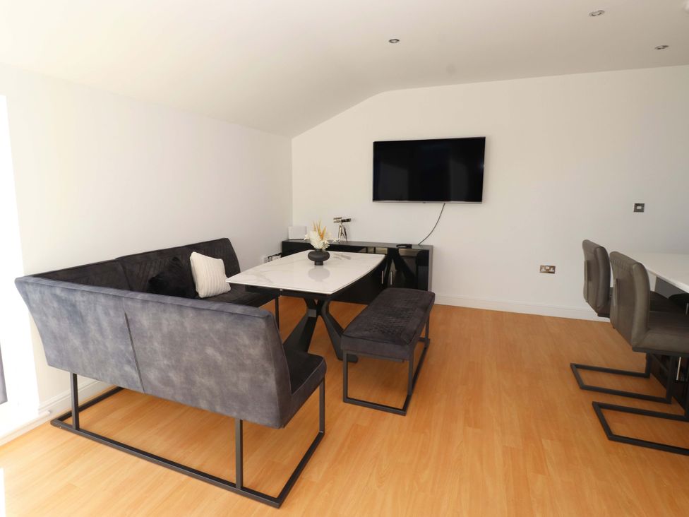 A dining room with a sofa and table at 1 Marina View in Pwllheli