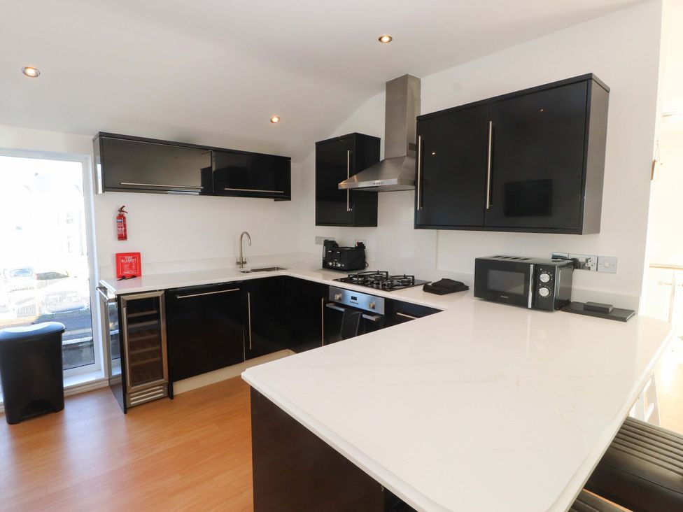 A kitchen with a stove and microwave at 1 Marina View Pwllheli