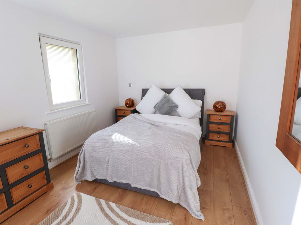 A bedroom with a bed and nightstand at 1 Marina View in Pwllheli