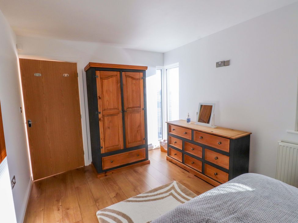 A bedroom with a wardrobe and dresser at 1 Marina View in Pwllheli