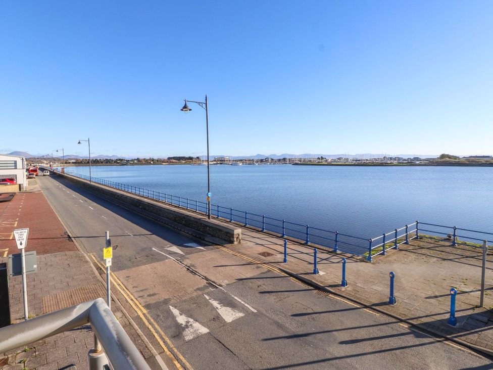 A view of a waterfront area with a road and railing at 1 Marina View Pwllheli