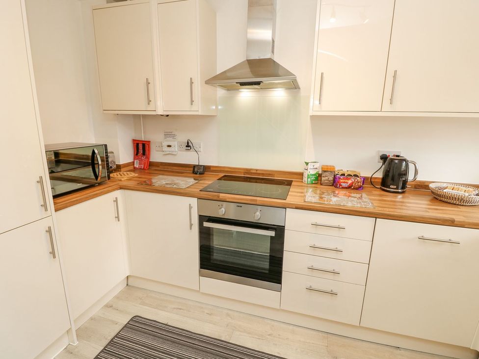 A kitchen with a microwave, oven, kettle, and kitchen cabinets at Harbour View Poole