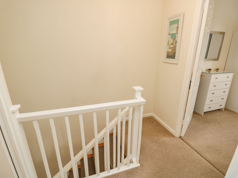 A hallway with a staircase and a dresser at Harbour View Poole