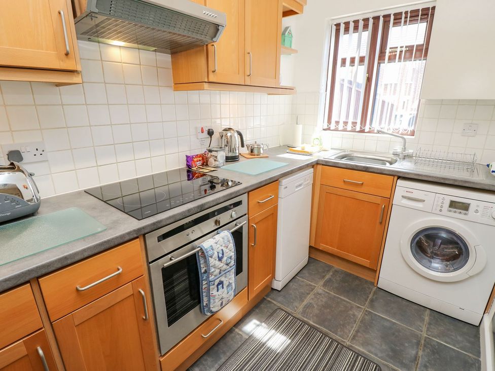 A kitchen with appliances and cabinets at Poole Quay Cottage in Poole