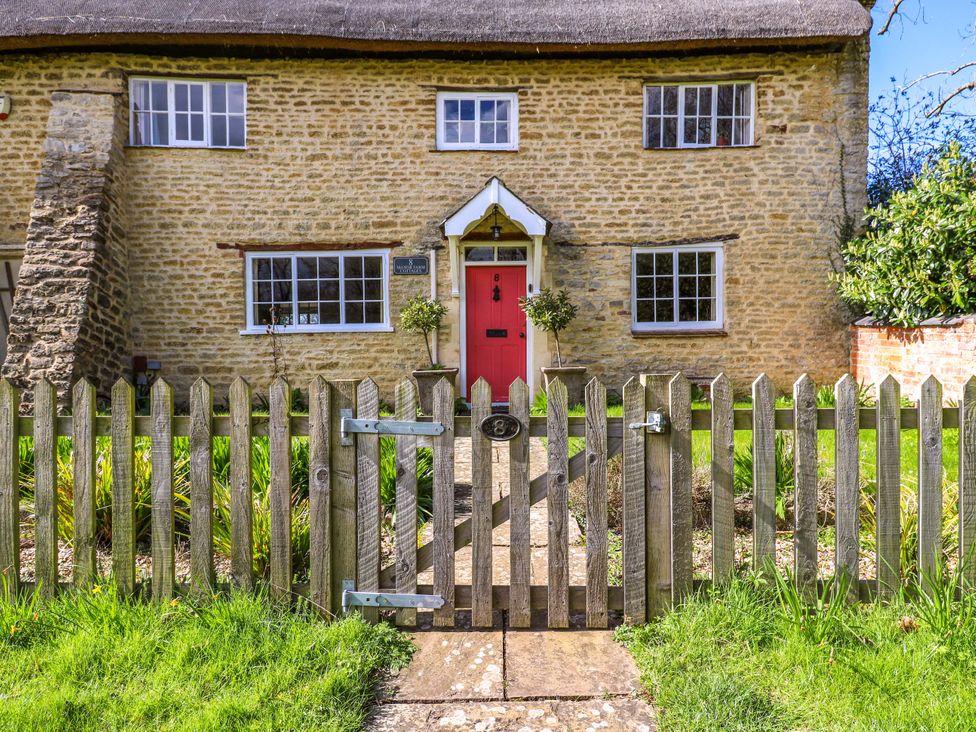 A house with a pink door and a wooden fence at Manor Farm Cottages in Loughton, Milton Keynes