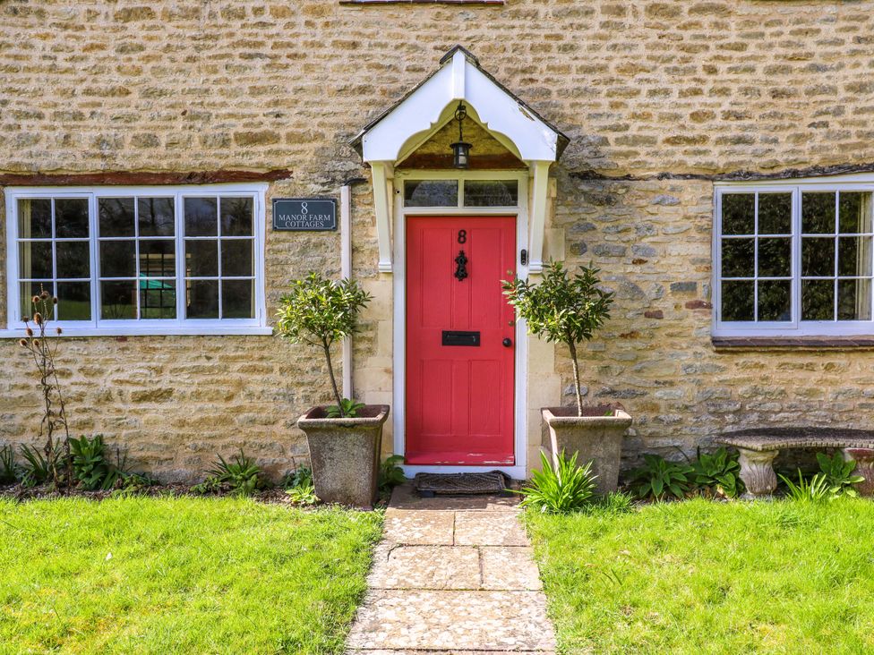 A front door with plants and a sign at Manor Farm Cottages Loughton Milton Keynes