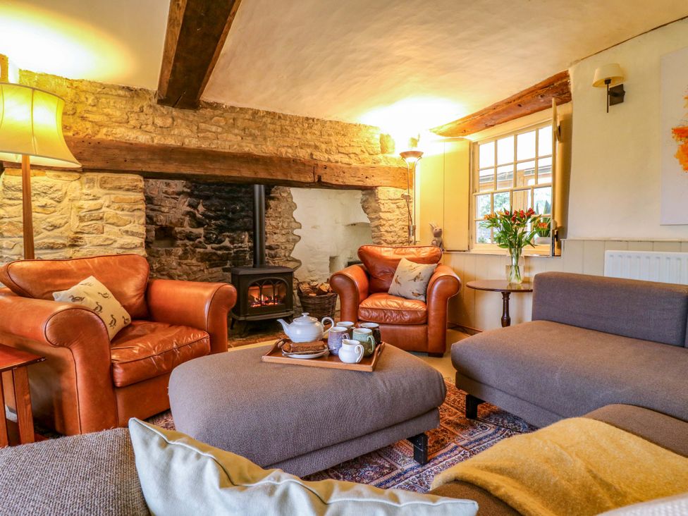 A living room with a fireplace and seating area at Manor Farm Cottages in Loughton, Milton Keynes