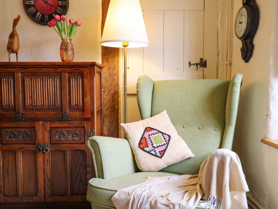 A living room with an armchair and a cabinet at Manor Farm Cottages in Loughton, Milton Keynes