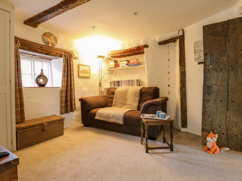 A living room with a sofa, coffee table, and shelves at Manor Farm Cottages in Loughton, Milton Keynes