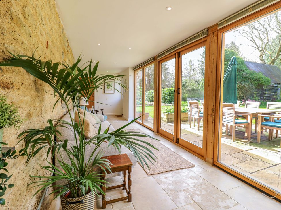 A sunroom with a sofa and plants at Manor Farm Cottages, Loughton, Milton Keynes