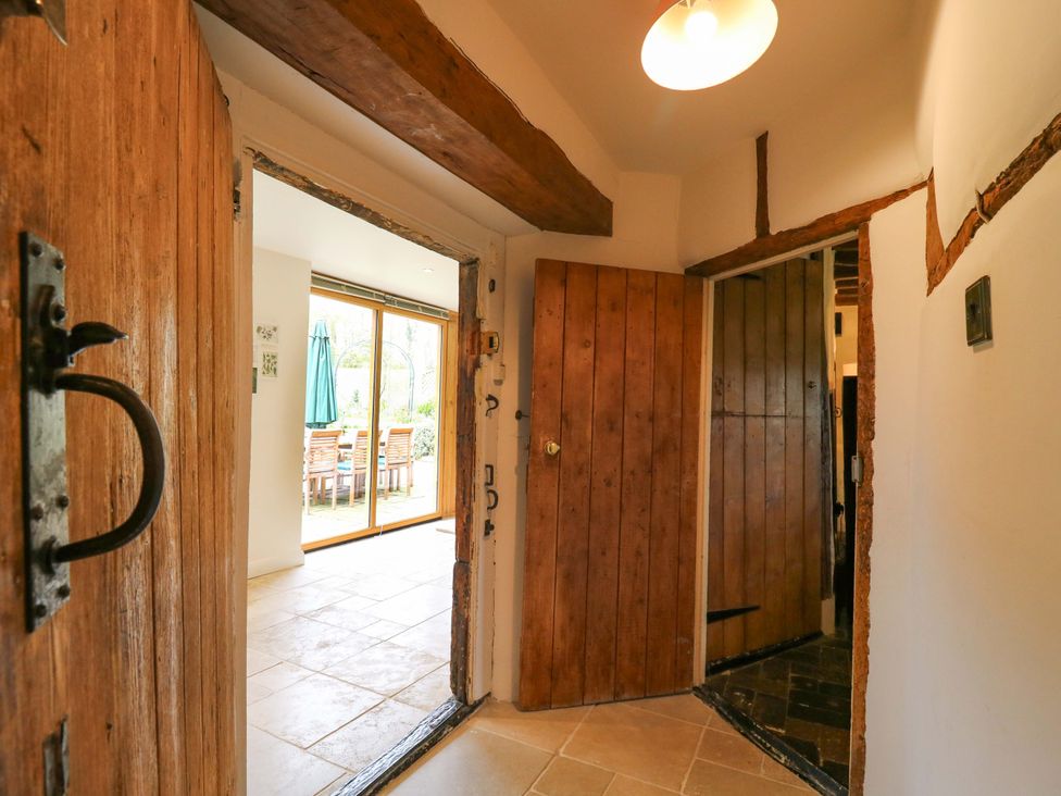 A hallway with wooden doors and a sliding door leading to an outdoor area at Manor Farm Cottages, Loughton, Milton Keynes