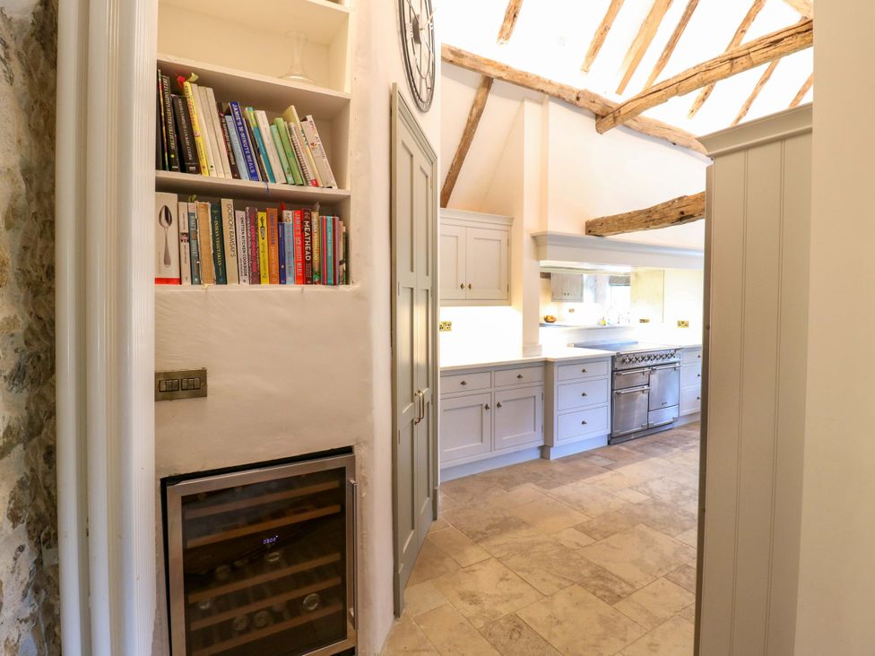 A kitchen with a bookshelf and wine cooler at Manor Farm Cottages in Loughton, Milton Keynes