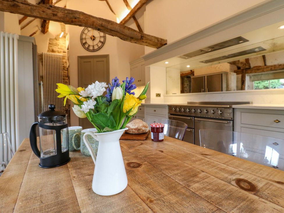 A kitchen with a table featuring flowers and coffee press at Manor Farm Cottages, Loughton, Milton Keynes