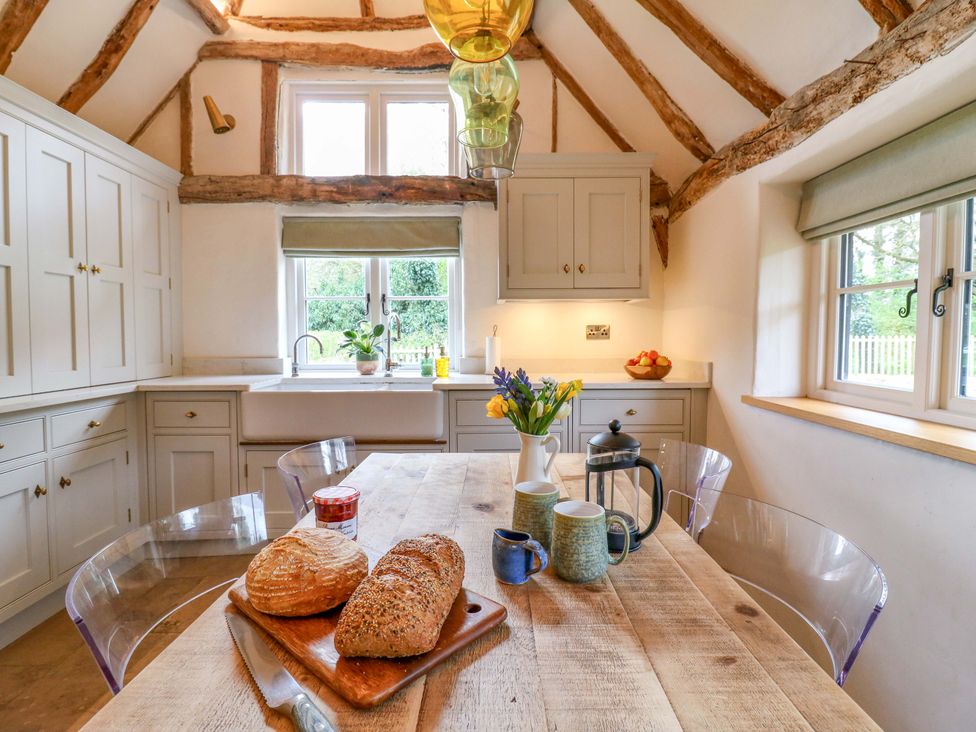 A kitchen with a wooden table and bread at Manor Farm Cottages, Loughton, Milton Keynes