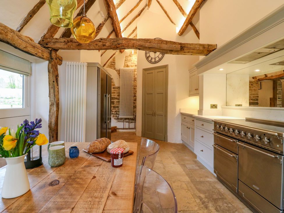 A kitchen with wood beams and appliances at Manor Farm Cottages in Loughton, Milton Keynes