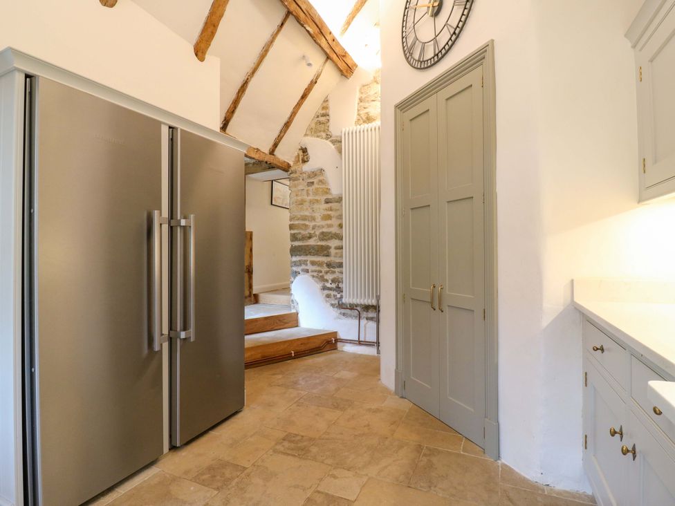 A kitchen with a refrigerator and a clock at Manor Farm Cottages, Loughton, Milton Keynes