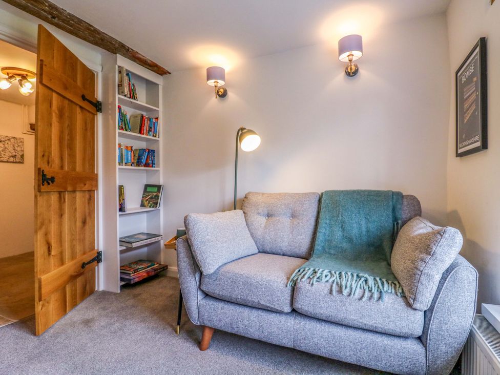 A living room with a sofa and bookshelf at Manor Farm Cottages, Loughton, Milton Keynes