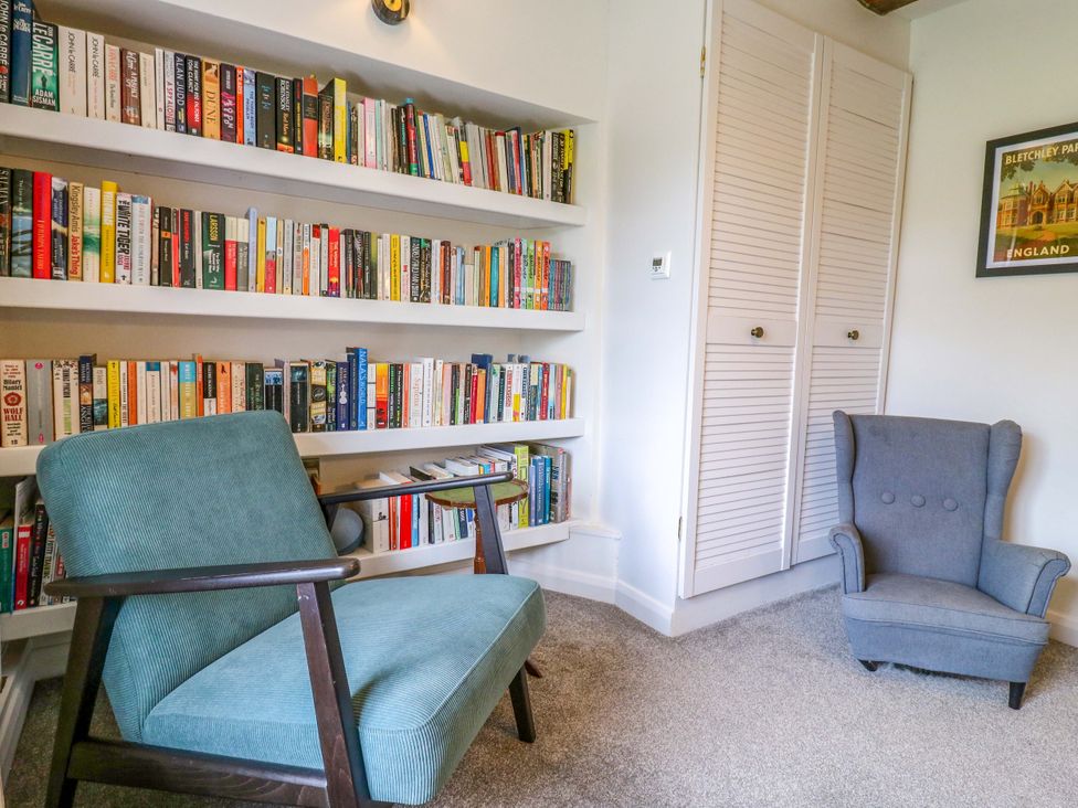 A reading room with bookshelf and two chairs at Manor Farm Cottages in Loughton, Milton Keynes