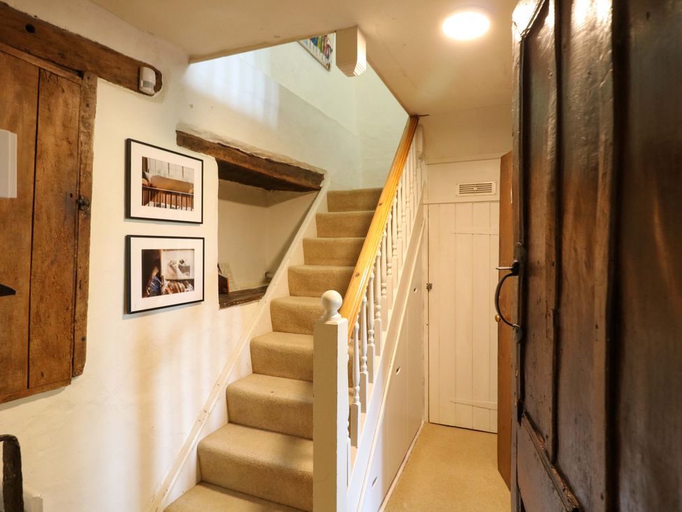 A hallway with staircase and pictures on the wall at Manor Farm Cottages Loughton, Milton Keynes