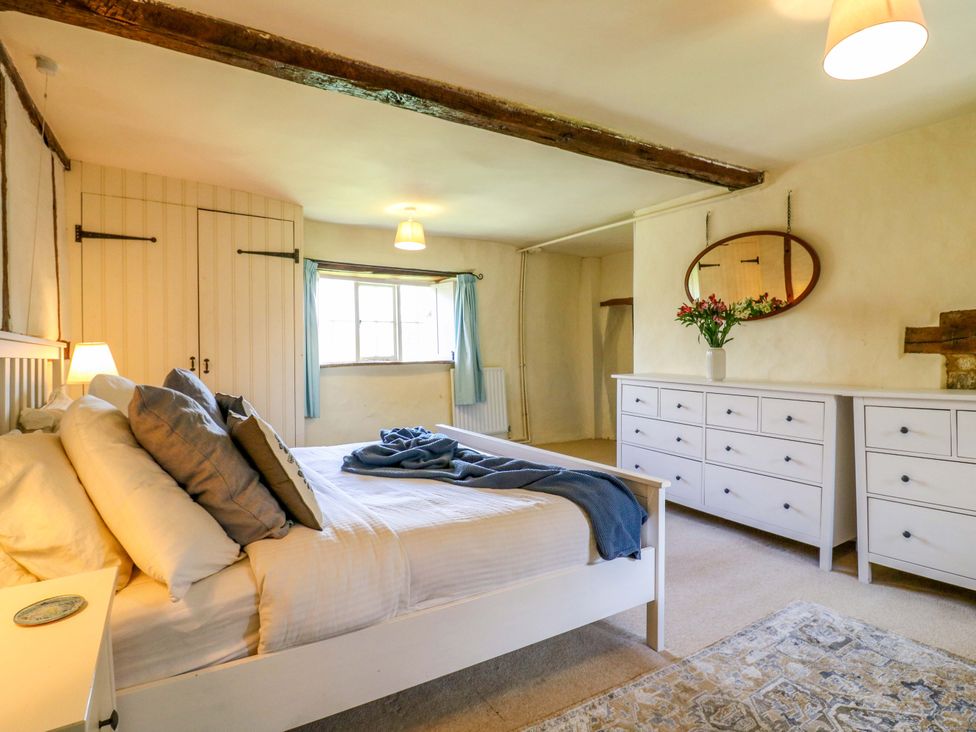 A bedroom with a bed and a dressing table at Manor Farm Cottages in Loughton, Milton Keynes