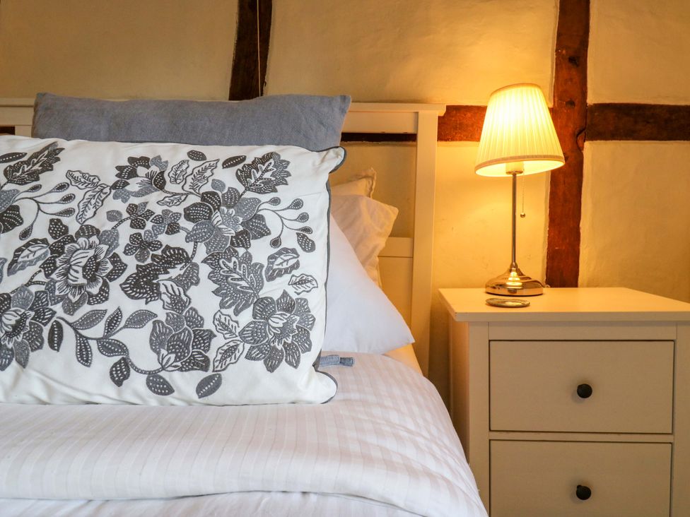 A bedroom with a bed, lamp, and bedside table at Manor Farm Cottages, Loughton, Milton Keynes