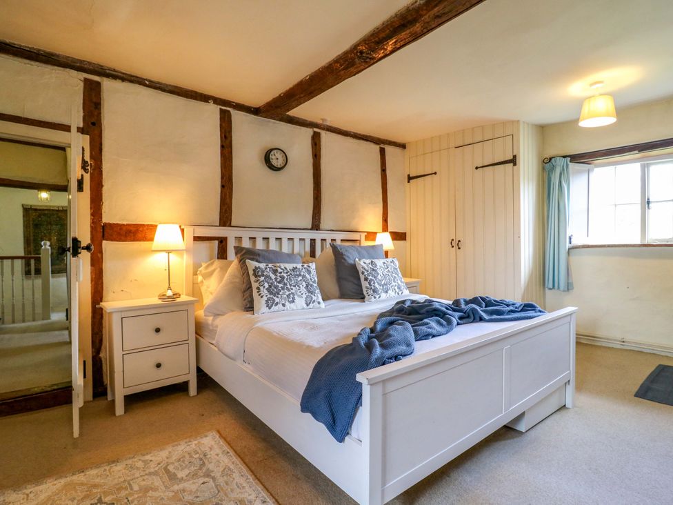 A bedroom with a bed and a wardrobe at Manor Farm Cottages in Loughton, Milton Keynes