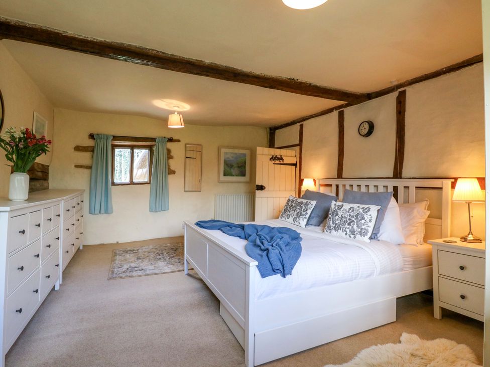 A bedroom with a bed and dresser at Manor Farm Cottages in Loughton, Milton Keynes