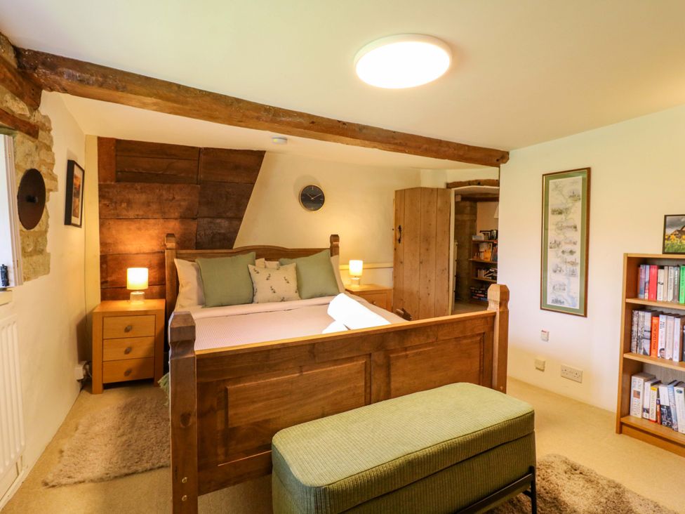 A bedroom with a bed and bookshelves at Manor Farm Cottages in Loughton, Milton Keynes