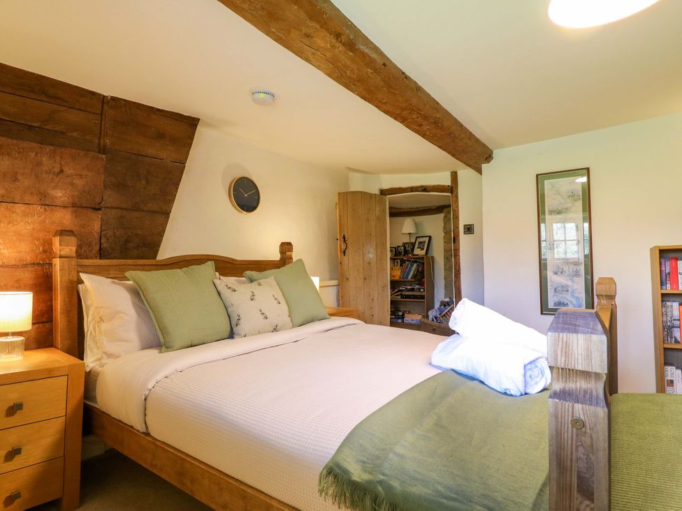 A bedroom with a bed and wardrobe at Manor Farm Cottages in Loughton, Milton Keynes