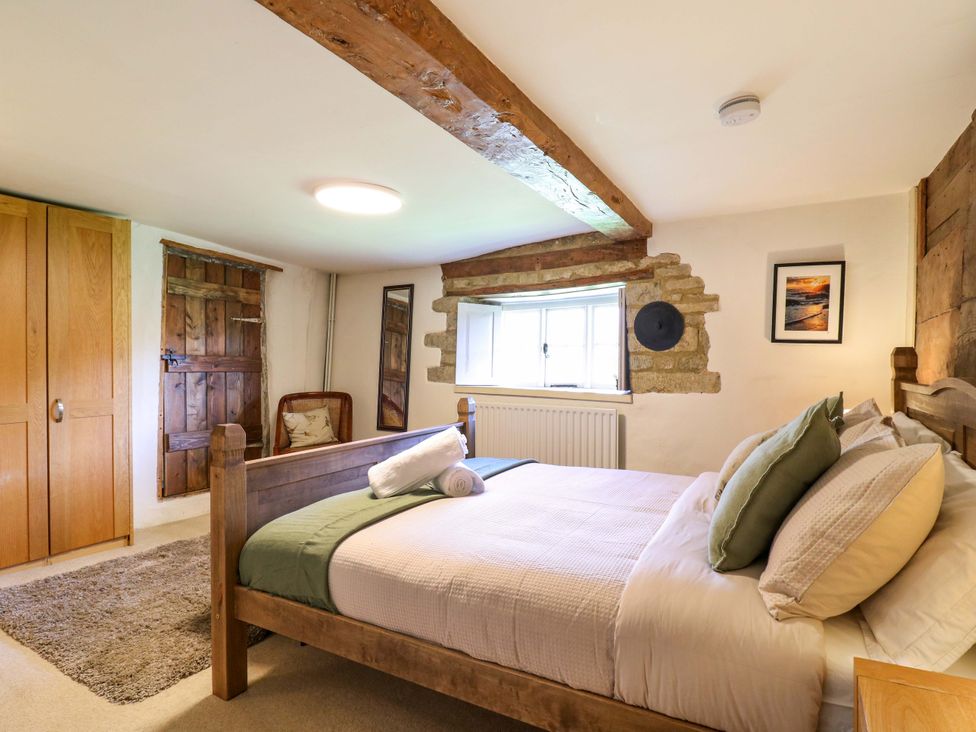 A bedroom with a bed and a wardrobe at Manor Farm Cottages in Loughton, Milton Keynes