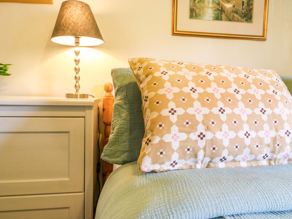 A bedroom with a patterned pillow and lamp at Manor Farm Cottages in Loughton, Milton Keynes