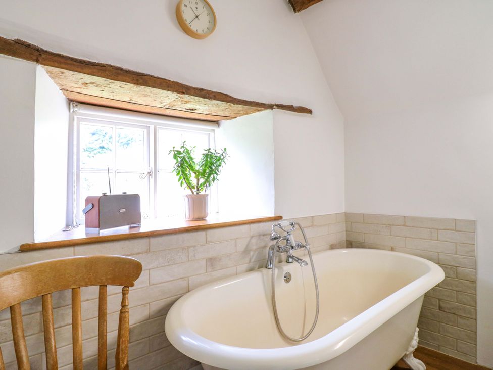 A bathroom with a bathtub and window at Manor Farm Cottages Loughton, Milton Keynes