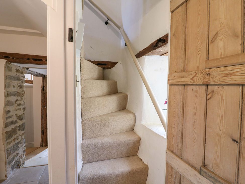 A staircase with a wooden door and stone wall at Manor Farm Cottages in Loughton, Milton Keynes